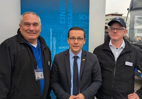 Das Bild zeigt drei Männer vor einem Roll-Up des Vereins WEISSER RING e.V. 